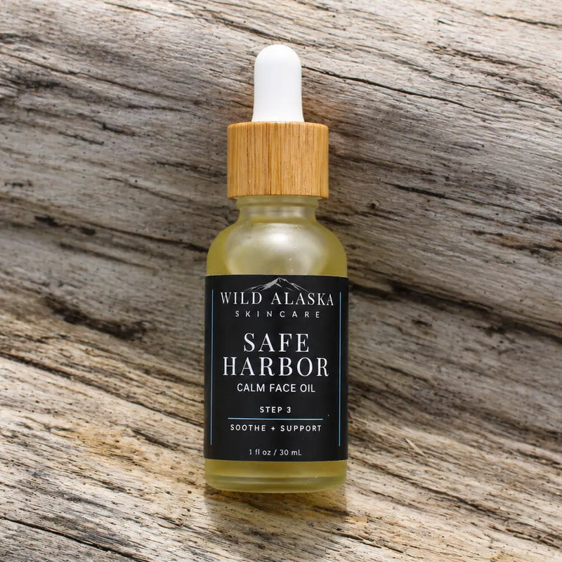 Bottle of Wild Alaska Skincare Safe Harbor Calm Face Oil on a wooden surface