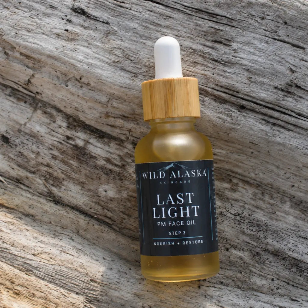 Bottle of Wild Alaska Last Light PM Face Oil on a wooden surface