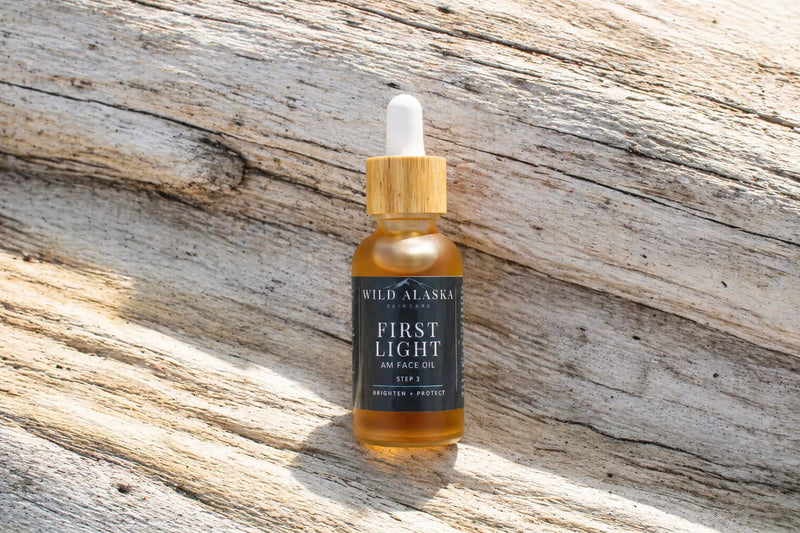 Bottle of Wild Alaska First Light AM Face Oil on a wooden surface