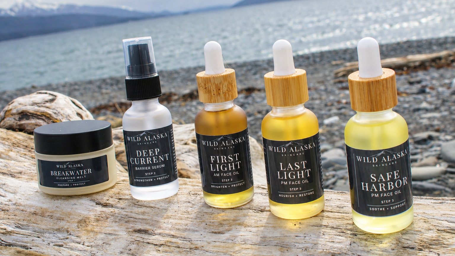 Set of five Wild Alaska Company skincare products on a wooden surface with a scenic background.