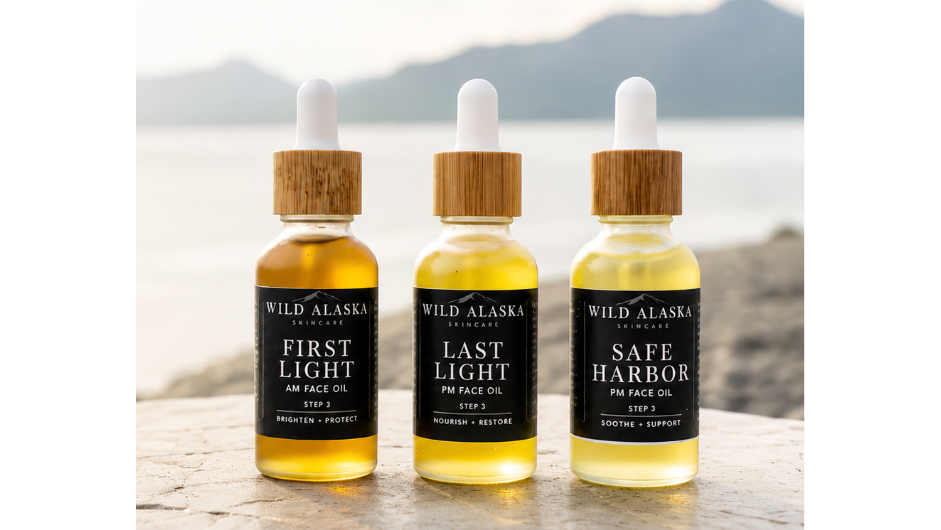 Three bottles of Wild Alaska Spirits on a rocky surface with a scenic background