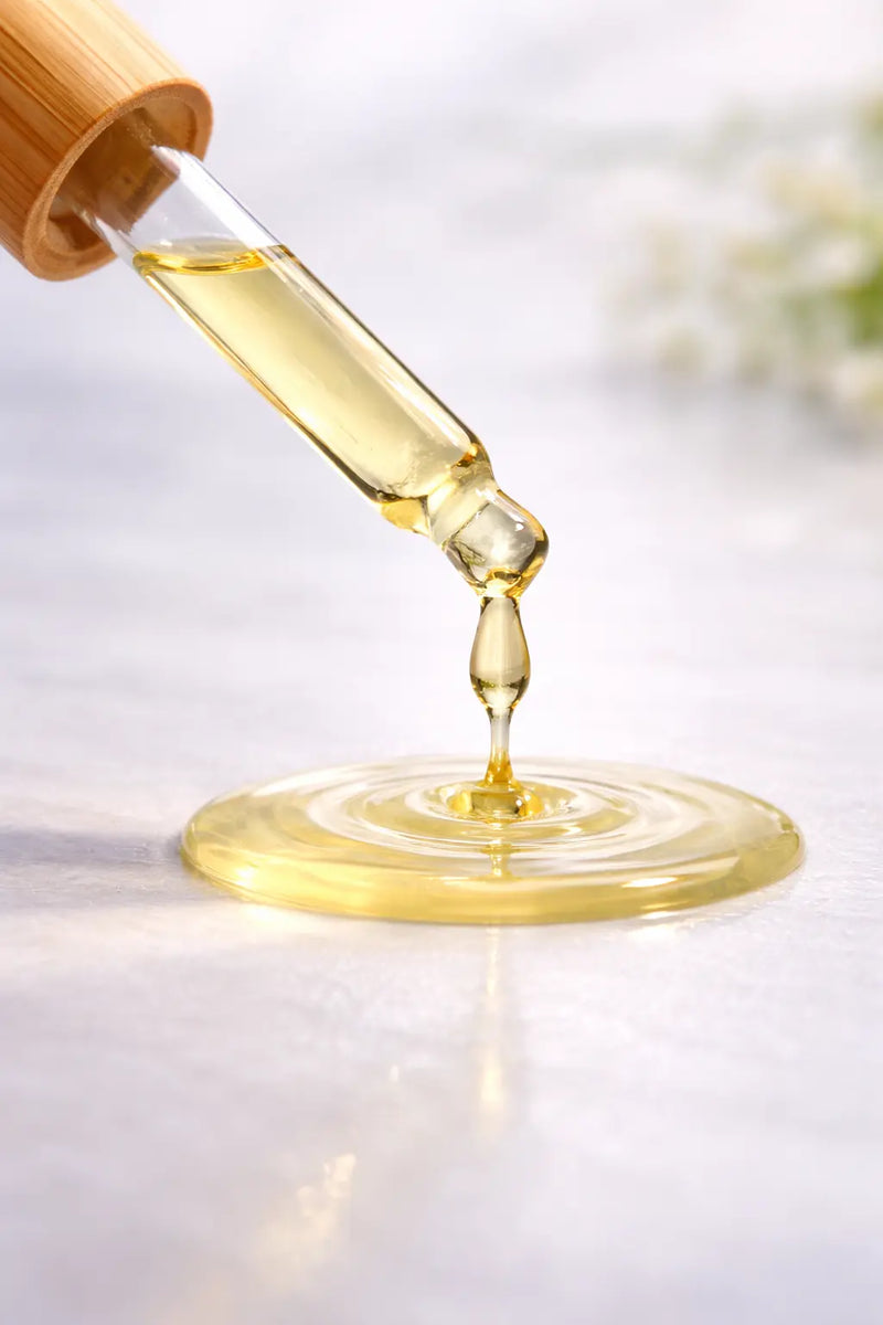 Dropper with yellow liquid dripping onto a light surface