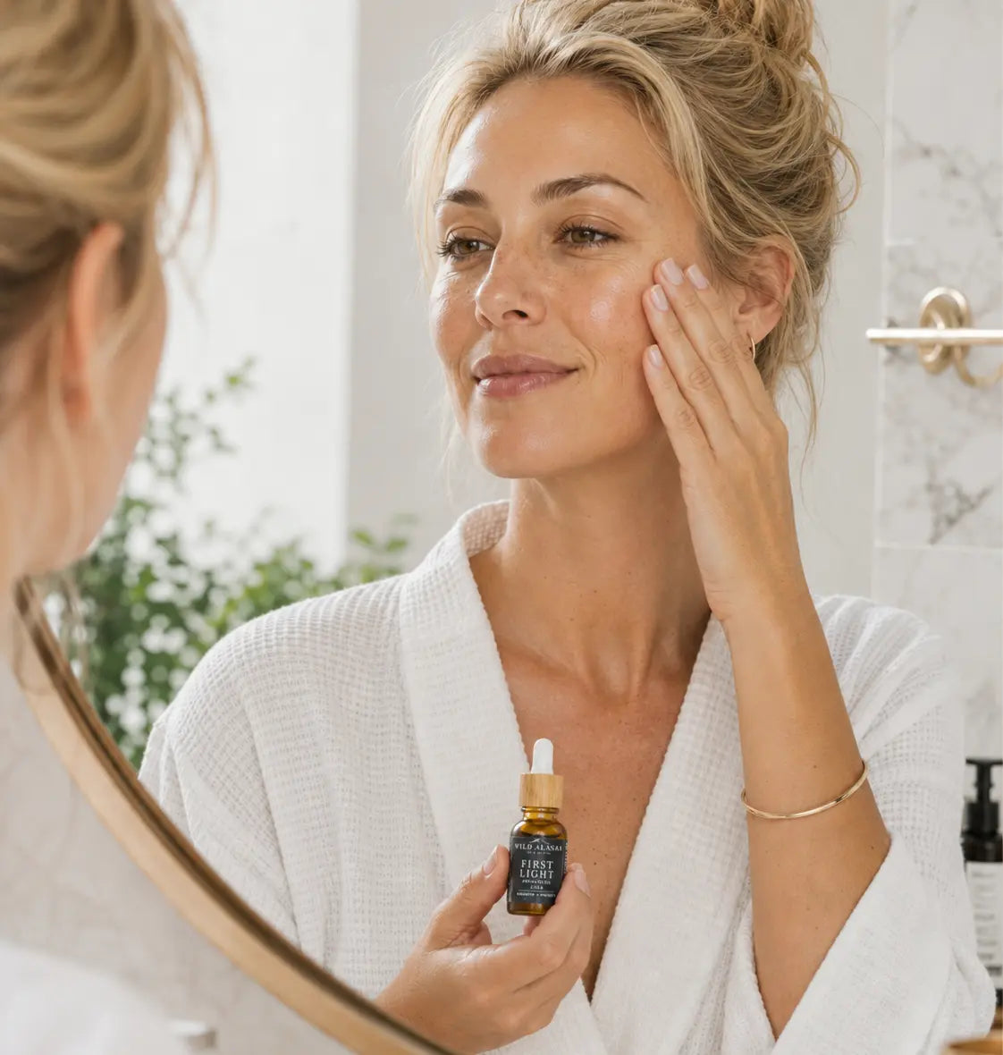 Woman applying skincare serum in front of a mirror