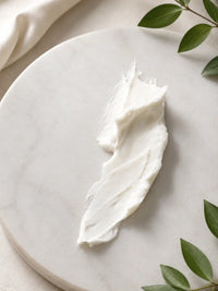 Whipped body butter on a marble plate with green leaves