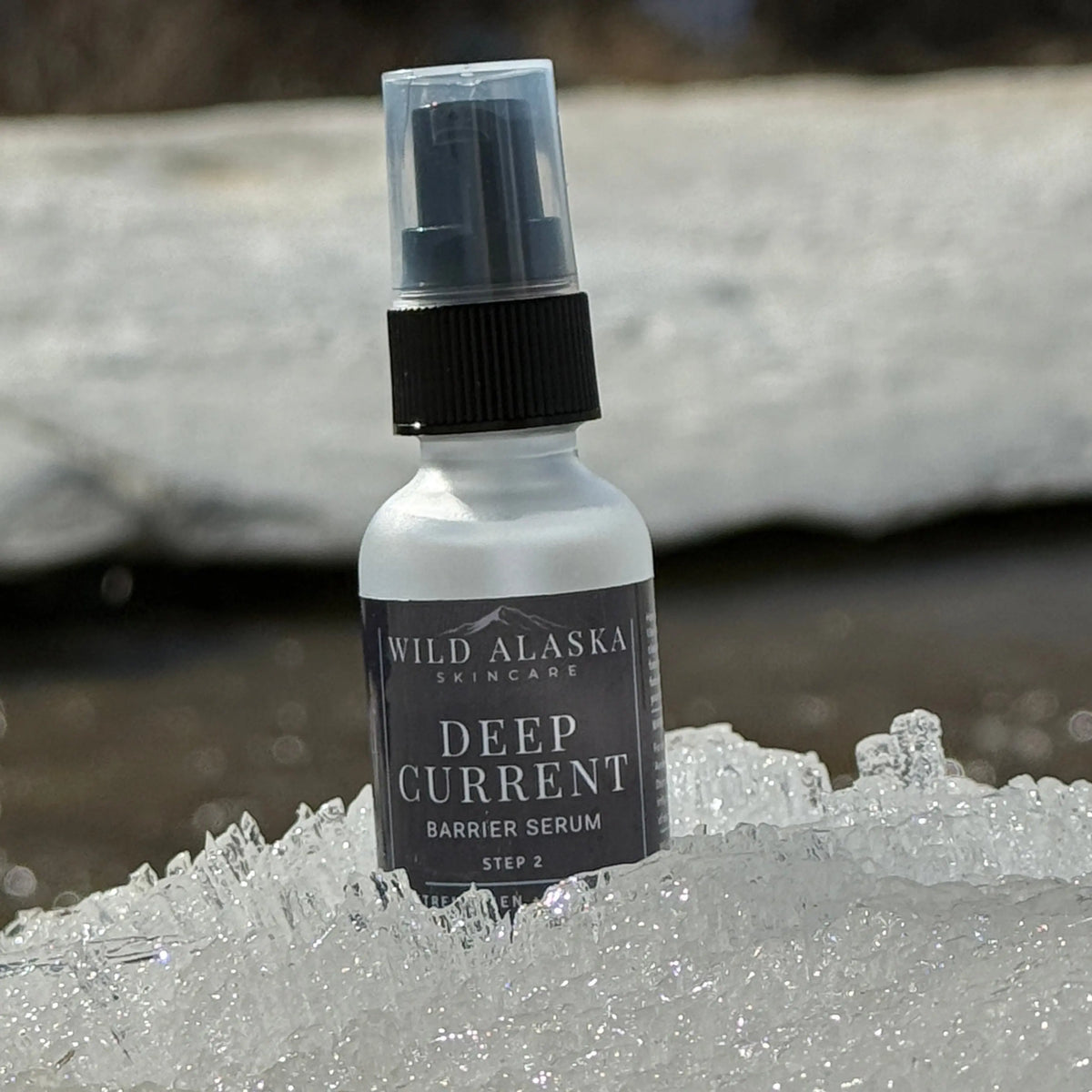 Bottle of Wild Alaska Skincare Deep Current Barrier Serum on a icy surface with blurred natural background