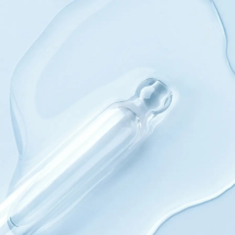 Clear dropper with liquid on a light blue background